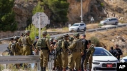 Israeli security forces inspect the scene of a shooting near the West Bank Jewish settlement of Tekoa, July 16, 2023. Authorities say a Palestinian gunman opened fire on a car, wounding three including two girls and sparking a manhunt.