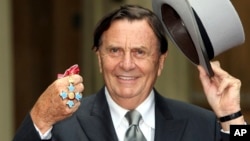 FILE - Australian entertainer Barry Humphries poses for pictures after he received his Most Excellent Order of the British Empire from Britain's Queen Elizabeth II at Buckingham Palace, London, on Oct. 10, 2007. (Steve Parsons/Pool Photo via AP)