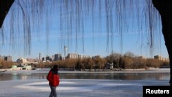 FILE - A man walks by a frozen lake at a park during winter solstice in Beijing, China Dec. 22, 2023.