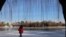 FILE - A man walks by a frozen lake at a park during winter solstice in Beijing, China Dec. 22, 2023.