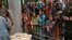Women and children wait for free food at a distribution point in Lahore, Pakistan, June 27, 2023.