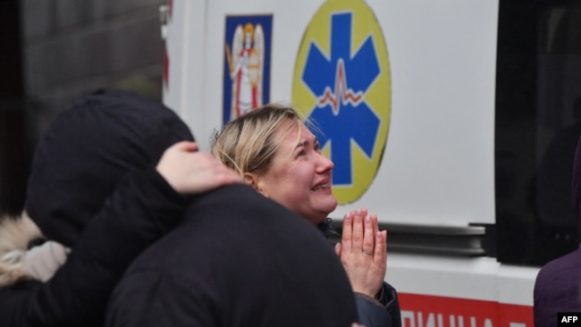 Local residents react outside a building damaged by a missile attack in Kyiv, Ukraine, Feb. 7, 2024.
