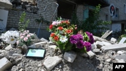This July 27, 2023, photo shows flowers displayed at a destroyed residential building in Izyum, Kharkiv region, Ukraine, where 47 civilians were killed in March 2022.
