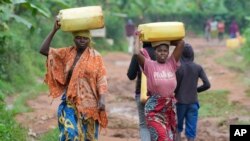Women carry water in Gahanga the outskirts of Kigali, Rwanda, April 4, 2024.