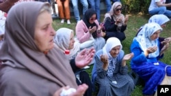 Para perempuan Muslim Bosnia berdoa di Visoko, di samping sebuah truk yang membawa 30 peti jenazah sisa-sisa korban genosida Srebrenica 1995 yang baru diidentifikasi, hari Minggu 9 Juli 2023. 