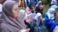 Muslim women pray in Visoko, Bosnia, July 9, 2023 next to a truck carrying 30 coffins with remains of the recently identified victims of the 1995 Srebrenica genocide. 