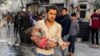 A Palestinian carries a casualty following an Israeli strike on a house, after a temporary truce between Hamas and Israel expired, in Rafah, in the southern Gaza Strip, Dec. 1, 2023.