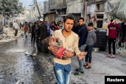 A Palestinian carries a casualty following an Israeli strike on a house, after a temporary truce between Hamas and Israel expired, in Rafah, in the southern Gaza Strip, Dec. 1, 2023.
