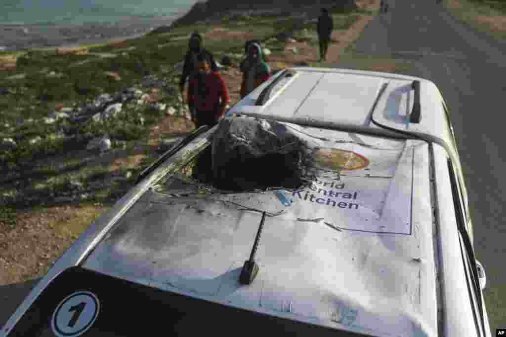 Palestinians inspect a vehicle with the logo of the World Central Kitchen wrecked by an Israeli airstrike in Deir al Balah, Gaza Strip, April 2, 2024. A series of airstrikes killed seven aid workers from the international charity, leading it to suspend delivery Tuesday of vital food aid to Gaza.&nbsp;