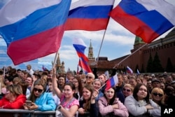 FILE - Thousands of people wave Russian national flags as they gather on Red Square to watch a concert dedicated to the Day of Russia in Moscow, Russia, June 11, 2023.