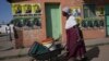FILE - An elderly woman pushes a wheelbarrow past campaign posters in Mabvuku on the outskirts of Harare, Zimbabwe, Dec. 9, 2023. 