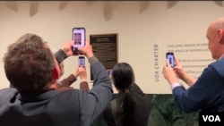 Los invitados fotografían la placa en honor a la VOA como un sitio histórico en el periodismo, el 2 de febrero de 2024 en Washington. (Cristina Caicedo Smit/VOA)