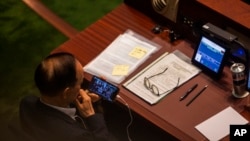 A pro-China lawmaker watches a video on a phone showing the 1945 Yalta Conference during the third reading of a bill that will overhaul district council elections in Hong Kong, July 6, 2023.