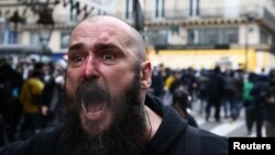 FILE: An injured man reacts during a demonstration as part of the ninth day of nationwide strikes and protests against French government's pension reform, in Paris, France, March 23, 2023. 