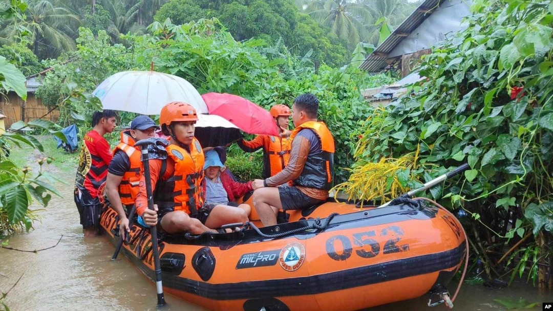In this photo provided by the Philippine Coast Guard, rescuers use a rubber boat as they evacuate residents to higher grounds following floods due to a tropical storm in Allen, Northern Samar province, Philippines, Sept. 1, 2024.