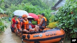 In this photo provided by the Philippine Coast Guard, rescuers use a rubber boat as they evacuate residents to higher grounds following floods due to a tropical storm in Allen, Northern Samar province, Philippines, Sept. 1, 2024.