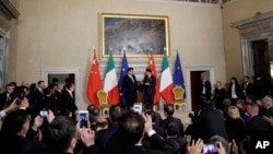 FILE - Chinese President Xi Jinping, background left, talks with then-Italian Prime Minister Giuseppe Conte during the signing of a memorandum of understanding in support of the Belt and Road Initiative, at Rome's Villa Madama, March 23, 2019.