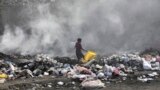 FILE - A woman walks through a landfill looking for salvageable items, in Port-au-Prince, Haiti, Saturday, July 1, 2023. (AP Photo/Odelyn Joseph)