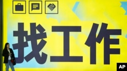 一名女子站在北京一个地铁站张贴的“找工作”的广告牌前。（2024年7月2日）