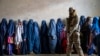 Seorang anggota Taliban berjaga saat perempuan menunggu untuk menerima jatah makanan yang didistribusikan oleh kelompok bantuan kemanusiaan, di Kabul, Afghanistan, 23 Mei 2023. (Foto: AP)
