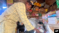 FILE - A man sells granulated sugar at his shop inside a market in Abuja, Nigeria, Oct. 27, 2023. Hundreds of people in Nigeria protested on Feb. 5, 2024, saying food costs are outpacing incomes. 