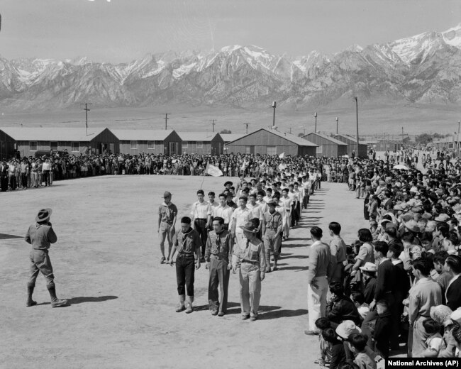FILE - In this photo provided by the National Archives, Japanese Americans, including American Legion members and Boy Scouts, participate in Memorial Day services at the Manzanar Relocation Center, an internment camp in Manzanar, Calif., May 31, 1942.