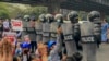 Demonstran memprotes kudeta militer di depan polisi anti huru hara di Yangon, Myanmar, Kamis, 18 Februari 2021. (Foto: AP)