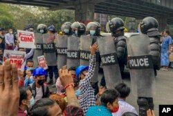 Demonstran melakukan protes terhadap kudeta militer di depan polisi anti-huruhara di Yangon, Myanmar Kamis, 18 Februari 2021. (Foto: AP)