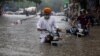 Dua pria mengendarai sepeda motornya mengarungi jalanan yang terendam banjir setelah hujan lebat di New Delhi, India (8/7). 