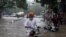 印度新德里的居民在被洪水淹没的街道上骑在电动车上。（2023年7月8日）
