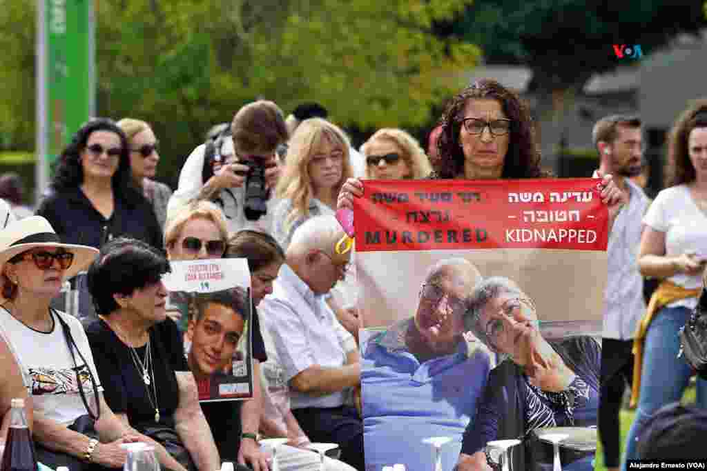 Una mujer posa con un póster con la imagen de dos de los secuestrados por Hamás durante una comida de shabbat organizada en la ciudad de Herzeliya, en recordación de los cautivos.