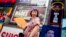A tour guide fans herself while working in Times Square as temperatures rise, July 27, 2023, in New York.