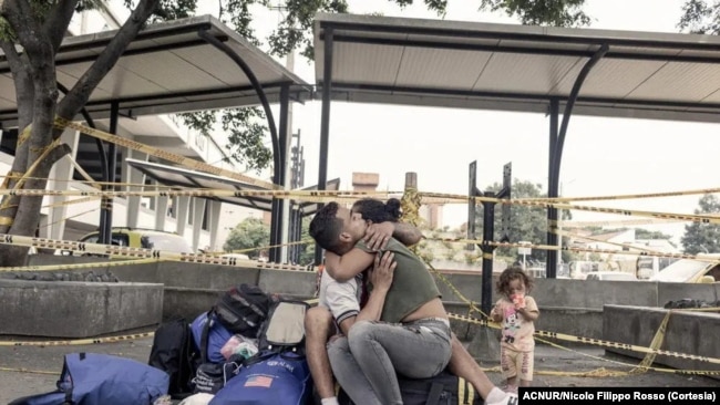María Fernanda Artigas abraza a su pareja, Endry Cordero Ávila, mientras su hija de 17 meses, Jerley, toma un refresco a la salida de la terminal de autobuses de Cali, Colombia en diciembre de 2022.