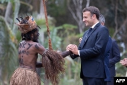 FILE - French President Emmanuel Macron shakes hands with a traditional dancer during a customary ceremony in his honour in Touho, north of New Caledonia, July 25, 2023.