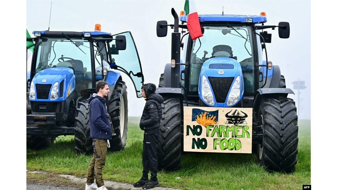 Petani Italia memarkir traktor mereka di sepanjang jalan saat melakukan aksi protes di dekat pintu masuk jalan raya di Melegnano, dekat Milan, 30 Januari 2023. (GABRIEL BOUYS / AFP)