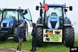 Petani Italia memarkir traktor mereka di sepanjang jalan saat melakukan aksi protes di dekat pintu masuk jalan raya di Melegnano, dekat Milan, 30 Januari 2023. (GABRIEL BOUYS / AFP)