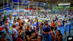 People sit inside a stadium after evacuating during a forest fire on the island of Rhodes, Greece, July 23, 2023.