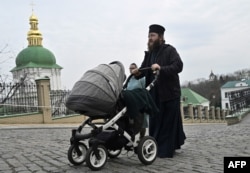A priest pushes a baby carriage as he walks at the Kyiv Monastery of the Caves, in Kyiv, March 24, 2023.