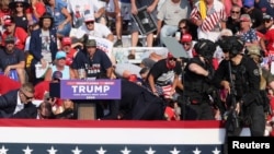 Republican presidential candidate and former U.S. President Donald Trump is assisted by U.S. Secret Service personnel after gunfire rang out during a campaign rally at the Butler Farm Show in Butler, Pennsylvania, July 13, 2024. 