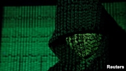 資料照片：二進位代碼被投影到一個戴兜帽的男人身上。