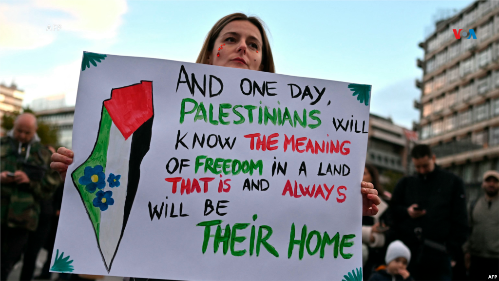 Mujer manifestante apoya al pueblo palestino en Belgrado, capital de Serbia. El cartel que sostiene dice: &quot;Y un día, los palestinos sabrán el significado de la libertad y de la tierra que es y será siempre su hogar&quot;.