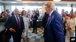 Former President Donald Trump looks to his valet Walt Nauta, left, as they visit Versailles restaurant on June 13, 2023, in Miami after he appeared in federal court.