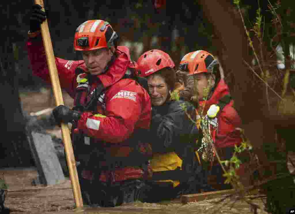 Firefighters rescue a woman from a homeless encampment that became surrounded by floodwater in the Santa Ana River during a rainstorm, Feb. 5, 2024, in San Bernardino, California.