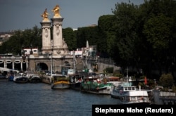 Sejumlah tongkang sedang bersandar di Sungai Seine dekat Jembatan Pont Alexandre III di Paris, Prancis, Kamis, 13 Juni 2024. (Foto: Stephane Mahe/Reuters)