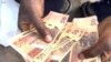 A Zimbabwean holds local currency in Harare on Feb. 13, 2024. Known as the dollar, bondnotes or ZWL, the currency has become nearly worthless since its introduction in 2014. (Columbus Mavhunga/VOA)