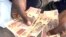A Zimbabwean holds local currency in Harare on Feb. 13, 2024. Known as the dollar, bondnotes or ZWL, the currency has become nearly worthless since its introduction in 2014. (Columbus Mavhunga/VOA)