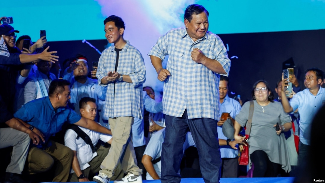 Bộ trưởng Quốc phòng Indonesia và ứng cử viên Tổng thống hàng đầu Prabowo Subianto (phải), cùng với người tranh cử Gibran Rakabuming Raka, con trai Tổng thống Joko Widodo, khiêu vũ sau khi phát biểu tại một sự kiện công bố kết quả đếm nhanh ở Jakarta, Indonesia, ngày 14/2/2024.
