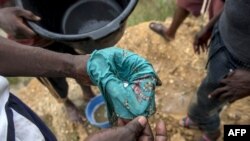 资料照片：2017年4月10日，加纳南部基比地区的一名非法淘金者使用汞来检查河沙中的黄金成分。（法新社照片）