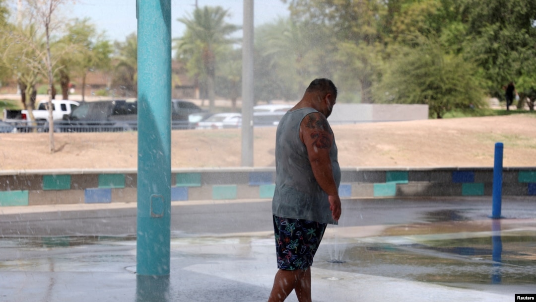 Seorang pria mendinginkan diri di taman air selama gelombang panas di Phoenix, Arizona, AS, 16 Juli 2023. (Foto: REUTERS/Liliana Salgado)