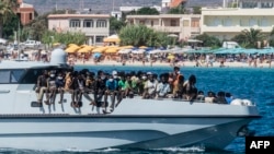 New migrants arrive on a Guardia di Finanza ship, in the Lampedusa harbor, Sept. 15, 2023. Good weather has seen a surge in arrivals across Italy in recent days, with more than 8,000 people landing in recent days.